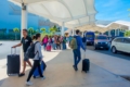 Travelers arriving at Cancun International Airport with luggage and signs for transfers.